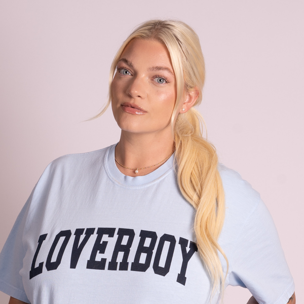 Woman wearing a light blue t-shirt with 'LOVERBOY' text on a plain background